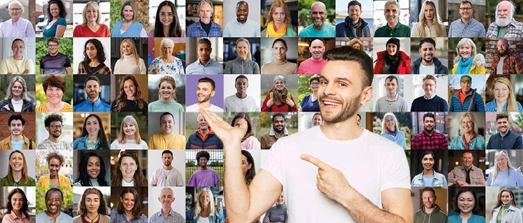 Een lachende man in een wit t-shirt wijst naar een collage van verschillende mensen van verschillende leeftijden en achtergronden, elk in hun eigen portret tegen verschillende achtergronden.
